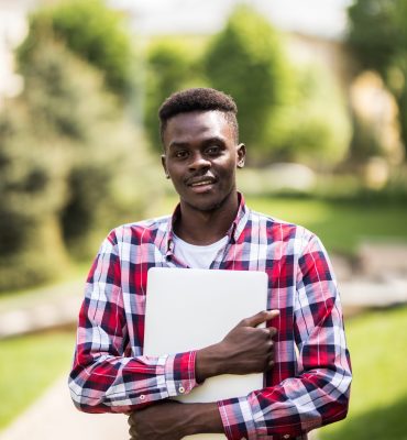 African American college student with laptop in the sunny day on the street